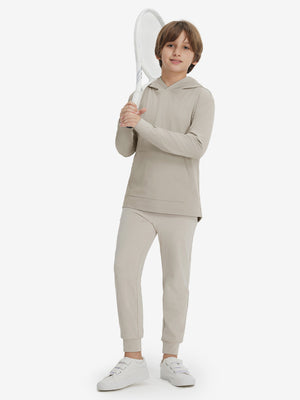 Model holding tennis racquet, wearing youth long sleeve hoodied with kangaroo pocket in khaki light, full-body.