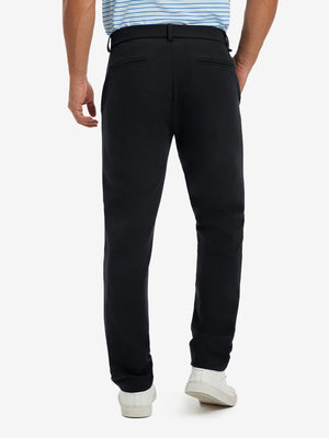 Back view of model wearing water-resistant golf stretch nylon pants, tailored stretch fit in black.