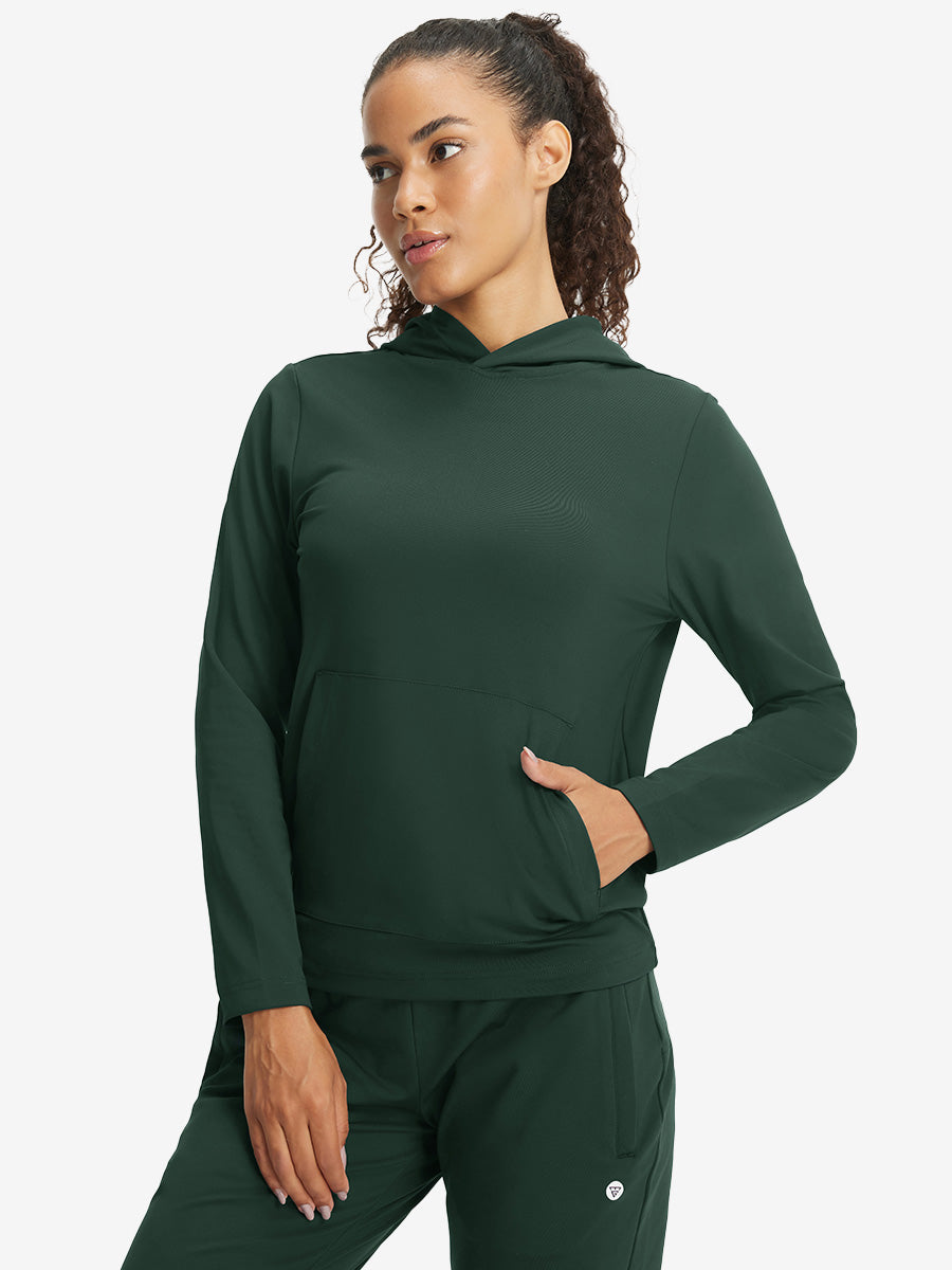 Model with one hand in side pocket wearing women's lightweight hoodies pullover in forest green.