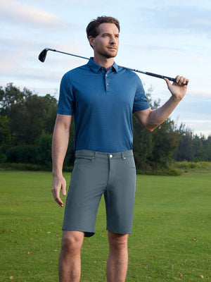 Model holding a golf club on course, styled in 4-way stretch performance solid shorts with dark grey