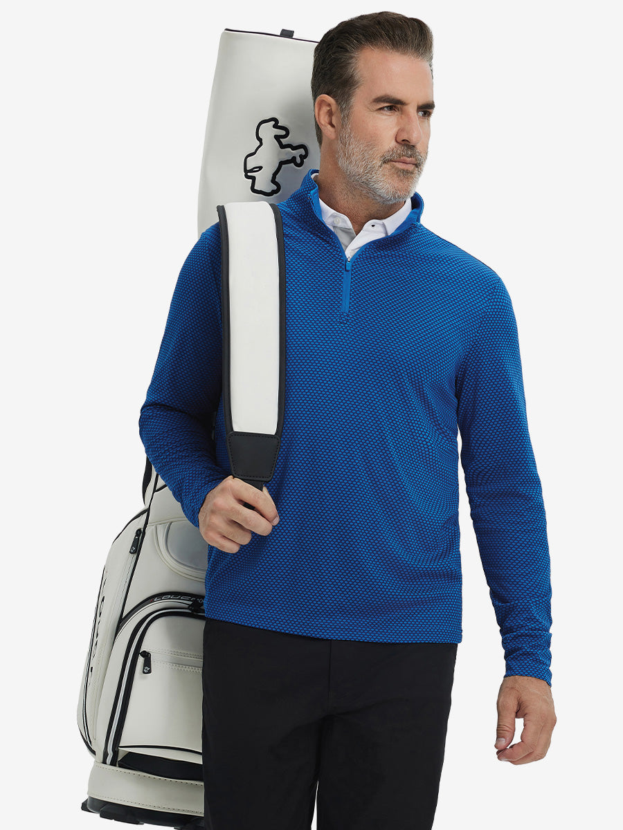 Model carrying a golf bag in jacquard quarter zip pullover in cobalt, blending comfort and style.