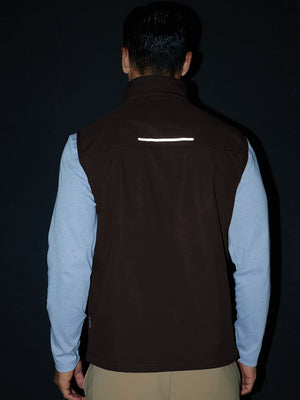 Model back half-body shot showcasing sleeveless softshell fleece outdoor vests with 6 pockets in coffee brown