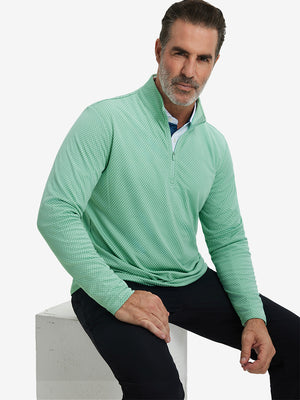 Model sitting and wearing jacquard quarter zip pullover in light green, showing relaxed casual posture.