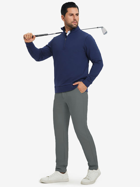 Model in dark blue top holding golf club on shoulder wearing lightweight moisture wicking dress pants in slate green.