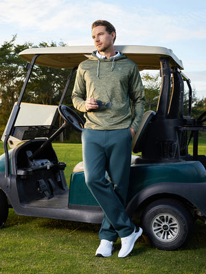 Model leaning on golf cart on course, wearing water-resistant fleece lined pants in saxony blue