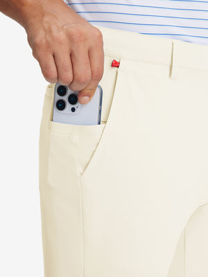 Hand placing an iPhone into pocket of soft lightweight casual golf pants with 5 pockets in khaki light.