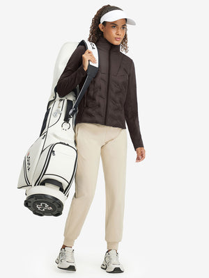 Model carrying a golf bag, wearing women's lightweight fleece-lined puffer jacket in coffee brown.