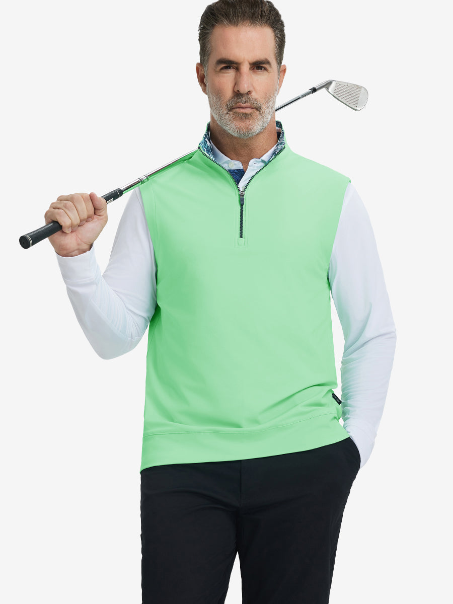 Model holding golf club, wearing print collar quarter zip golf vest in dark grey, upper body view.