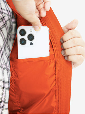 Close-up of boys full-zip fleece-lined puffer vest pocket holding a phone, practical detail in orange