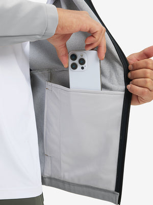 Hand placing an iPhone into pocket of water-resistant heat-tech softshell winter jacket with hood.