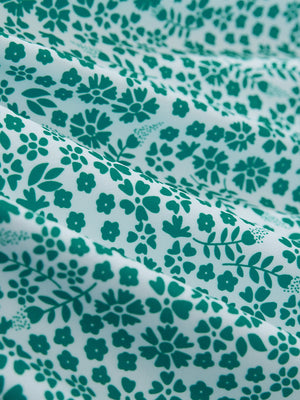 Close-up of white green florals stretch printed collarless henley golf shirts, showcasing texture and print details.