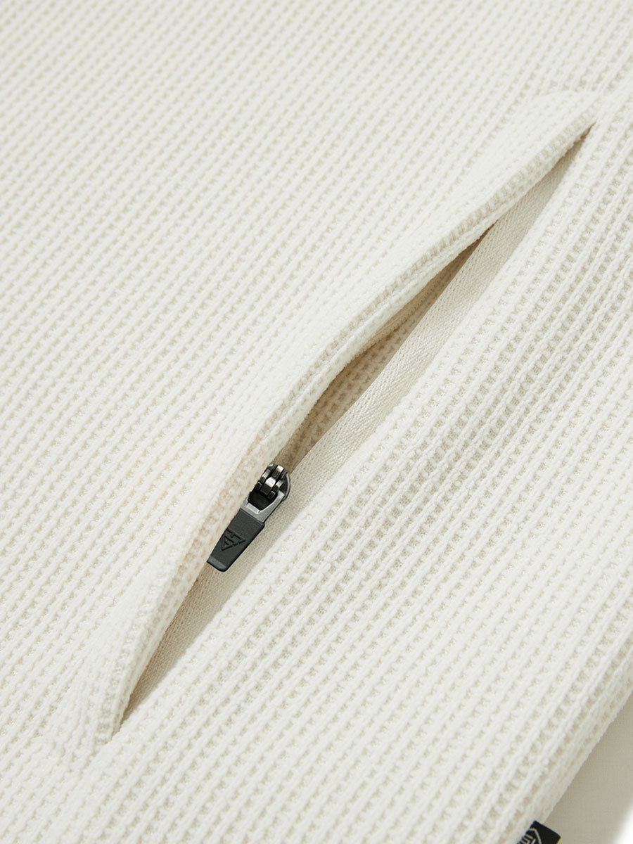 Close-up of jacket pocket showing fine stitching and insulation detail, textured insulated winter jacket, beige.