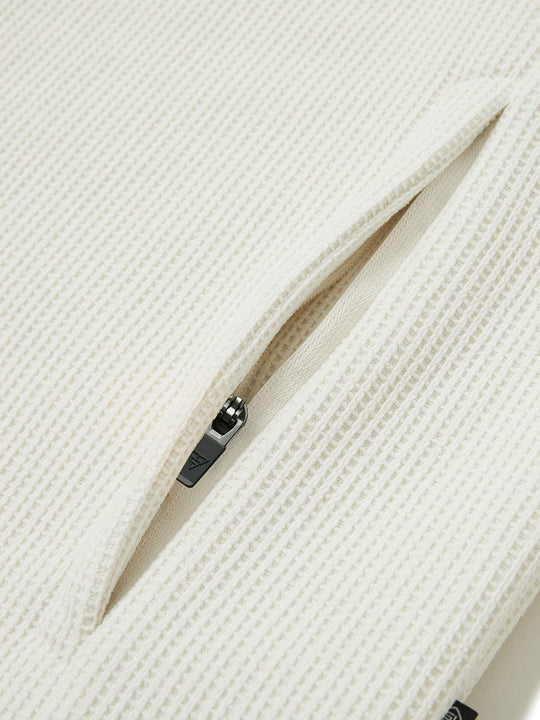Close-up of jacket pocket showing fine stitching and insulation detail, textured insulated winter jacket, beige.